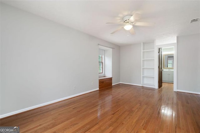 empty room with visible vents, ceiling fan, wood finished floors, and baseboards