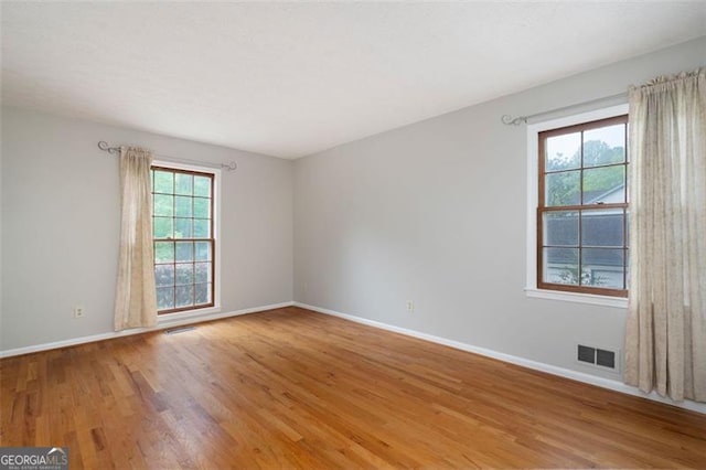 empty room with visible vents, baseboards, and light wood-style floors