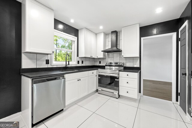 2302 Aurie Dr, Decatur, GA 30034 - kitchen featuring appliances with stainless steel finishes, wall chimney range hood, a sink, dark countertops, and white cabinets