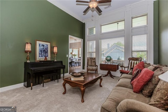 living room featuring a ceiling fan, baseboards, crown molding, and carpet floors