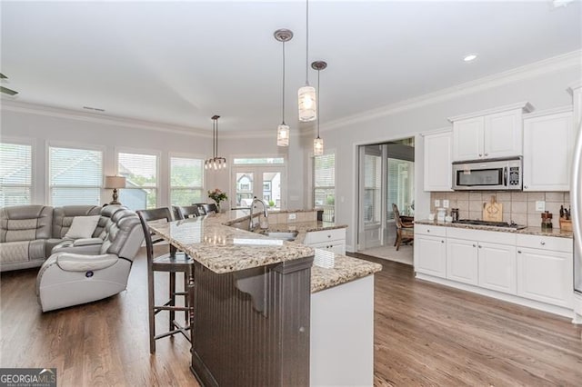 kitchen featuring open floor plan, a sink, stainless steel appliances, and light wood-type flooring