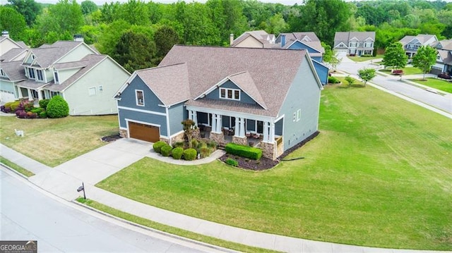 view of front of home with covered porch, a garage, a residential view, driveway, and stone siding