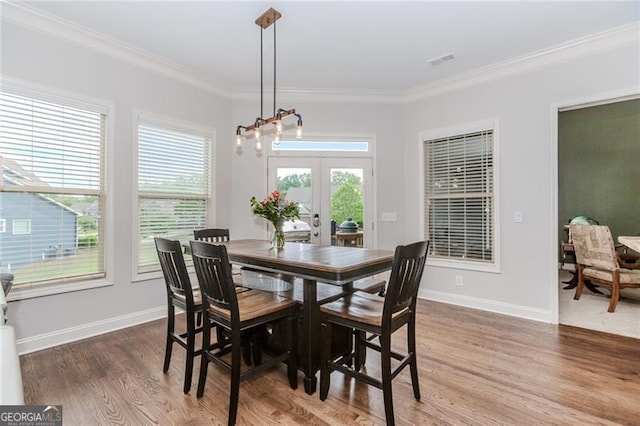 dining room with ornamental molding, visible vents, wood finished floors, and french doors