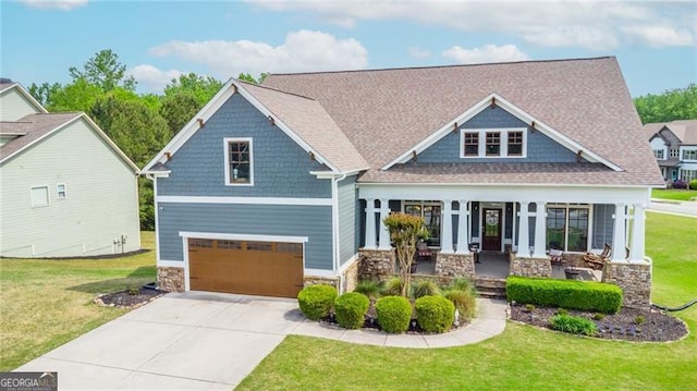 craftsman house featuring a garage, a porch, a front yard, and stone siding