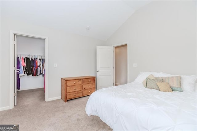 carpeted bedroom with a walk in closet, a closet, and vaulted ceiling