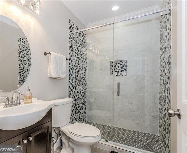 bathroom with vanity, toilet, ornamental molding, and a stall shower