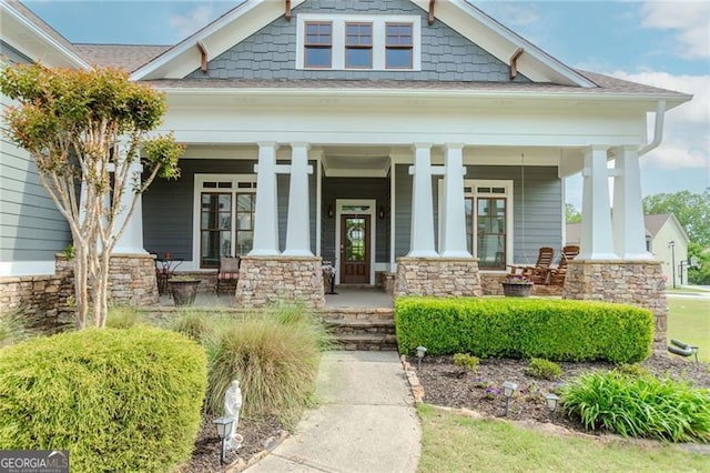 view of exterior entry with a porch and stone siding