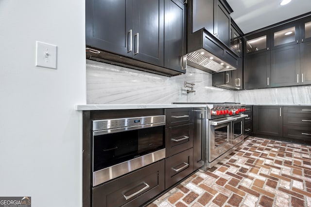 139 Thornhill Cir, Athens, GA 30607 - kitchen featuring brick floor, premium range hood, stainless steel appliances, backsplash, and glass insert cabinets