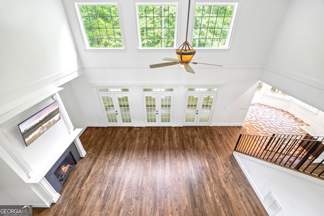 139 Thornhill Cir, Athens, GA 30607 - unfurnished living room featuring ceiling fan, french doors, a healthy amount of sunlight, a towering ceiling, and a lit fireplace