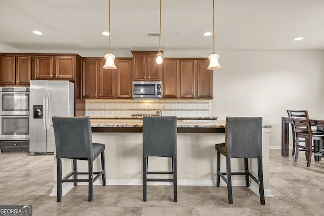 15 Manas Ct, Covington, GA 30016 - kitchen featuring a kitchen breakfast bar, backsplash, appliances with stainless steel finishes, and decorative light fixtures
