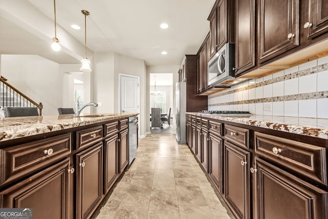 15 Manas Ct, Covington, GA 30016 - kitchen with a sink, stainless steel appliances, decorative light fixtures, light stone counters, and backsplash