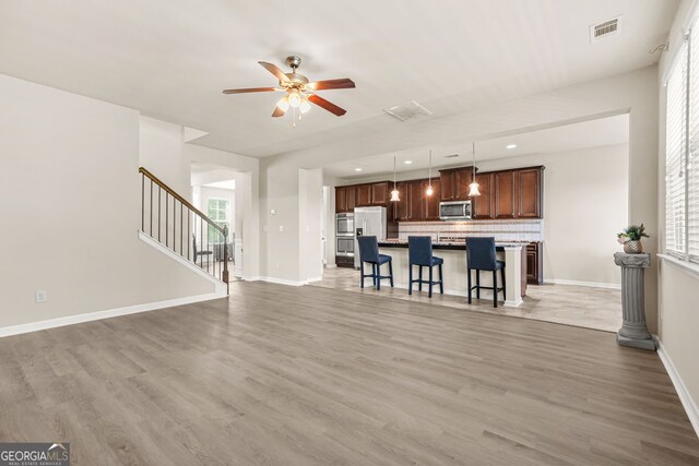 15 Manas Ct, Covington, GA 30016 - living room featuring stairs, light wood-style floors, ceiling fan, baseboards, and visible vents