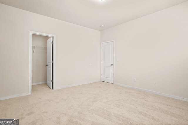 15 Manas Ct, Covington, GA 30016 - unfurnished bedroom featuring a walk in closet, a closet, baseboards, and light carpet