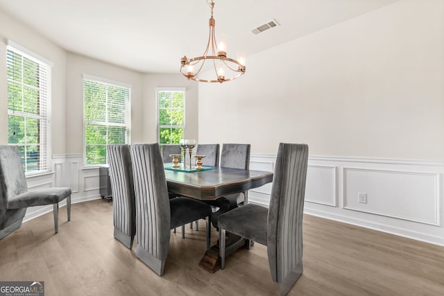 15 Manas Ct, Covington, GA 30016 - dining area with a chandelier, a wainscoted wall, visible vents, light wood-style flooring, and a decorative wall