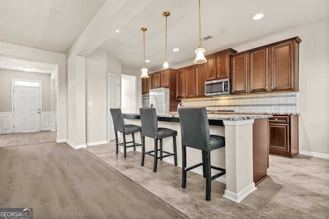 15 Manas Ct, Covington, GA 30016 - kitchen featuring stainless steel appliances, tasteful backsplash, a breakfast bar area, decorative light fixtures, and light stone counters
