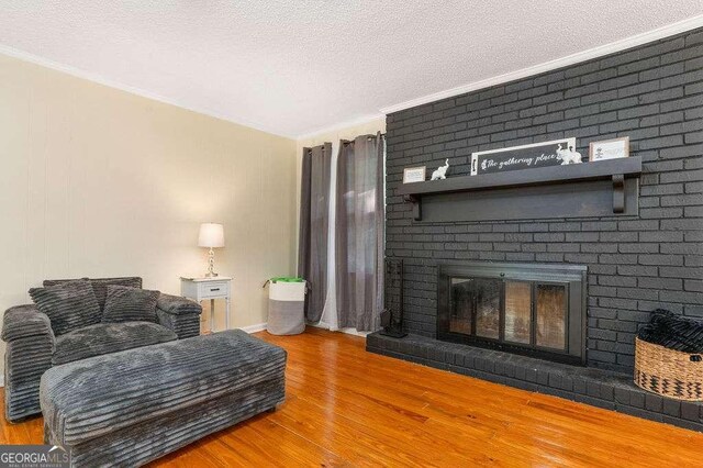 4393 Housworth Dr, Stonecrest, GA 30038 - living area featuring a brick fireplace, crown molding, baseboards, a textured ceiling, and wood finished floors