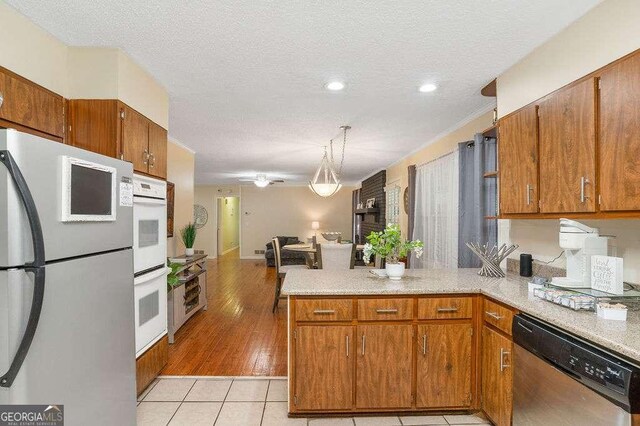 4393 Housworth Dr, Stonecrest, GA 30038 - kitchen featuring brown cabinetry, a peninsula, stainless steel dishwasher, and freestanding refrigerator