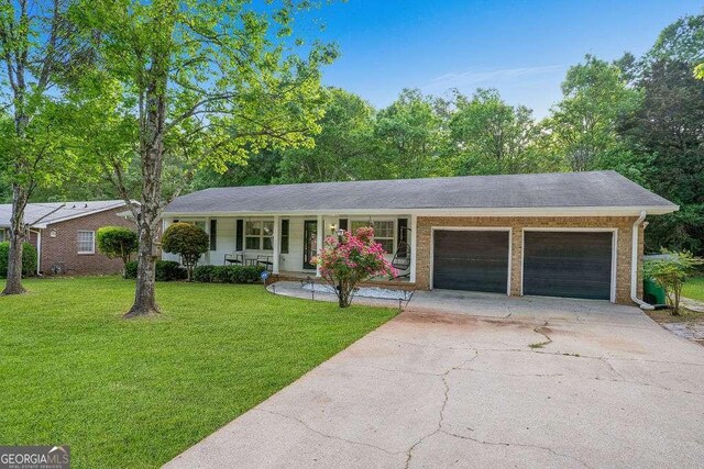 4393 Housworth Dr, Stonecrest, GA 30038 - ranch-style home with a porch, a front lawn, a garage, and concrete driveway