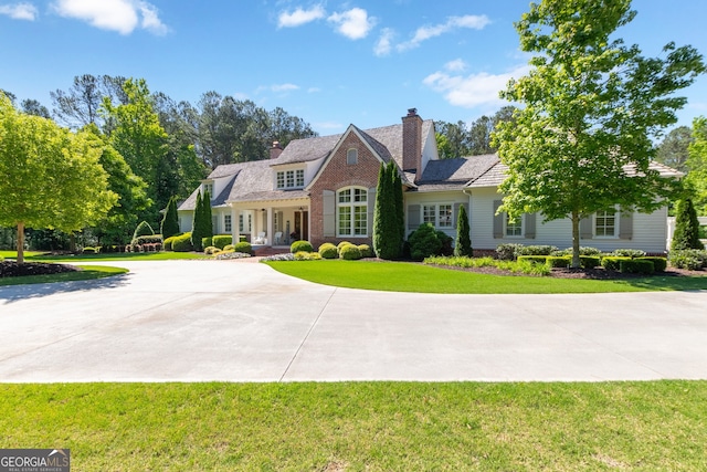 view of front facade featuring a front yard, curved driveway, and a chimney