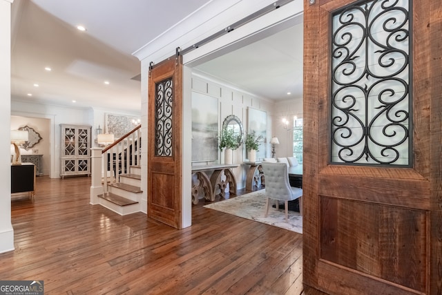 entryway featuring recessed lighting, stairway, a barn door, wood-type flooring, and ornamental molding
