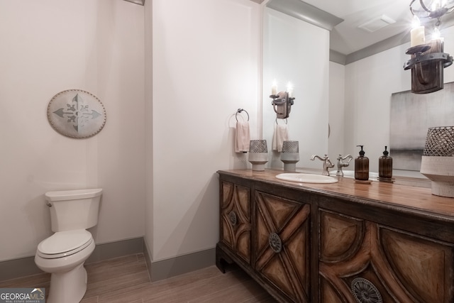 half bathroom featuring baseboards, wood finished floors, toilet, and vanity