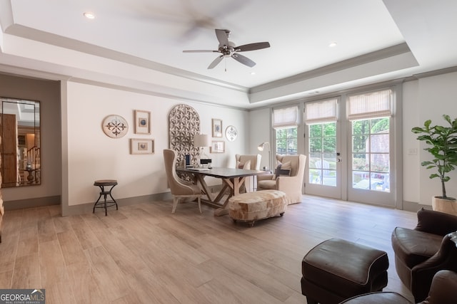 living area with recessed lighting, ornamental molding, ceiling fan, light wood finished floors, and a raised ceiling