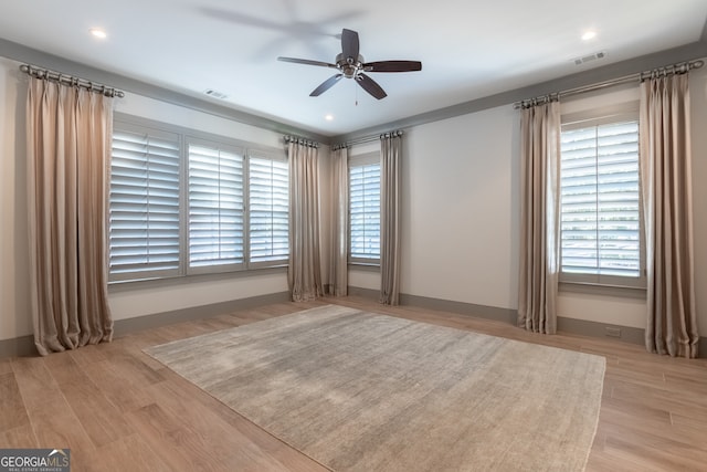 spare room featuring wood finished floors, visible vents, and ceiling fan
