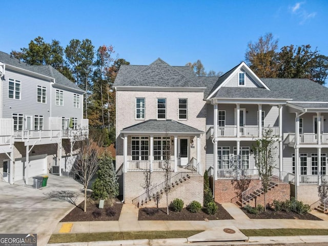rear view of house featuring a porch, concrete driveway, stairs, and a garage