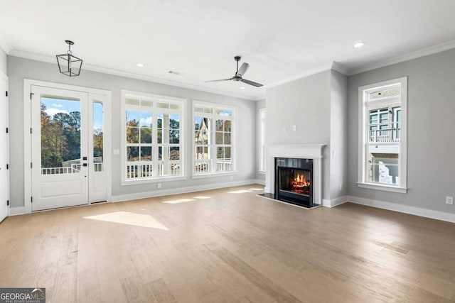 unfurnished living room with a glass covered fireplace, wood finished floors, and crown molding
