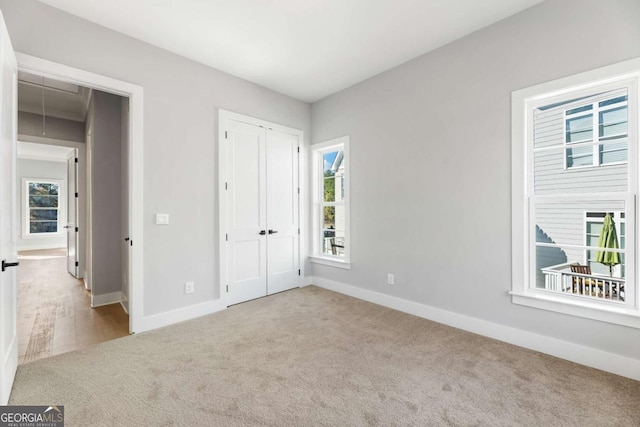 unfurnished bedroom featuring baseboards, attic access, a closet, and carpet flooring