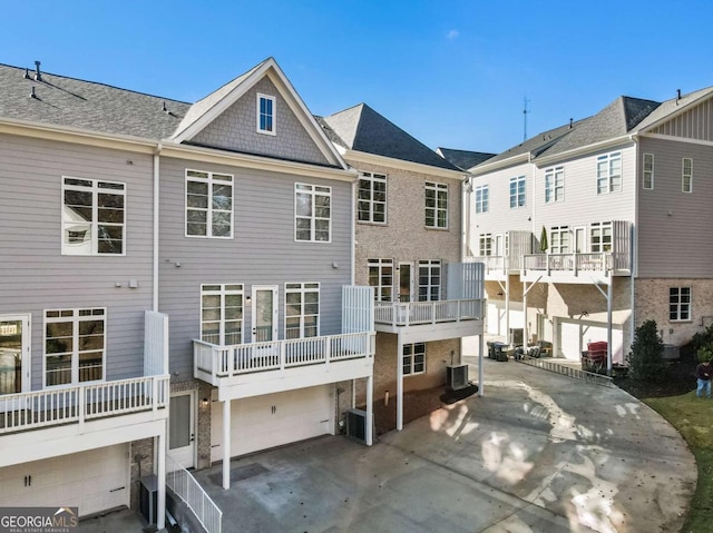 back of property featuring central AC unit, a residential view, and a garage