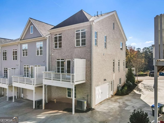 rear view of house featuring cooling unit, concrete driveway, brick siding, and a garage