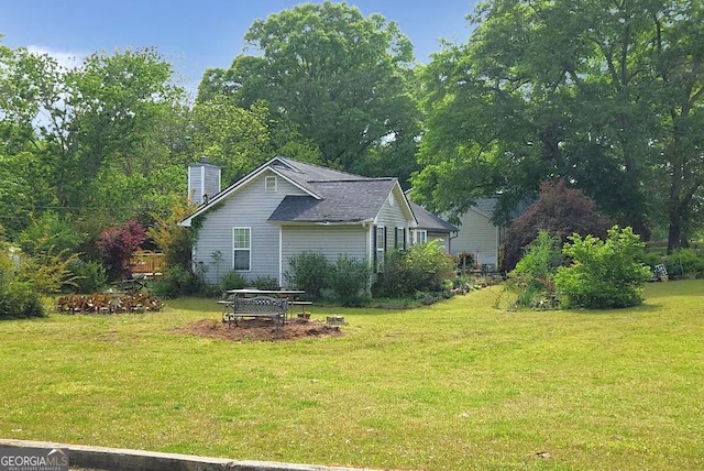 view of side of property with a yard and a chimney