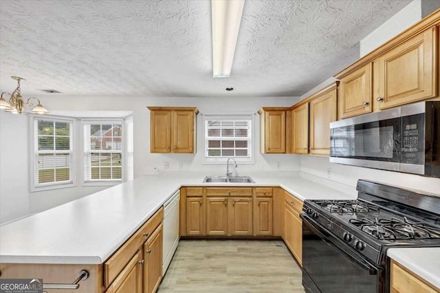 kitchen with light wood-style flooring, stainless steel microwave, black gas range oven, dishwasher, and a sink