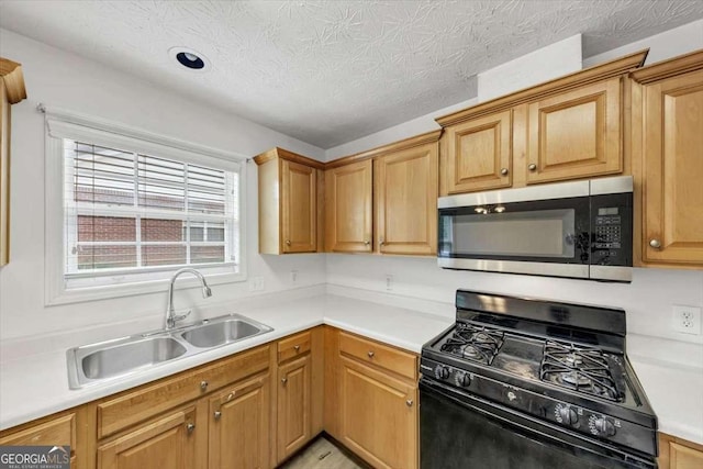 kitchen featuring stainless steel microwave, light countertops, gas stove, a sink, and a textured ceiling