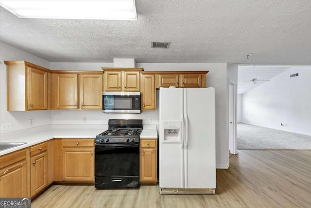 kitchen featuring stainless steel microwave, light wood-type flooring, white fridge with ice dispenser, visible vents, and black gas range