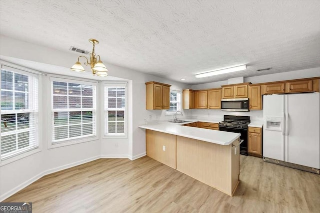 kitchen featuring stainless steel microwave, a sink, white refrigerator with ice dispenser, light wood-type flooring, and black gas range