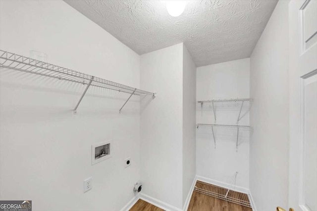 laundry room with laundry area, electric dryer hookup, hookup for a washing machine, baseboards, and wood finished floors