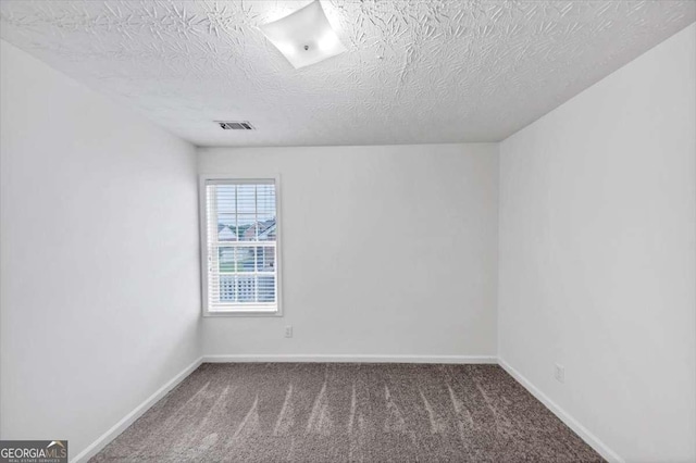 carpeted spare room with a textured ceiling, visible vents, and baseboards