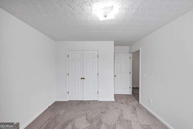 unfurnished bedroom with baseboards, a textured ceiling, a closet, and carpet flooring