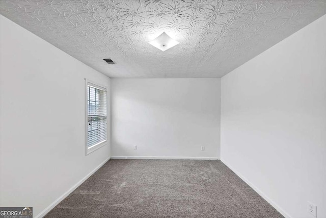 empty room with carpet, visible vents, baseboards, and a textured ceiling