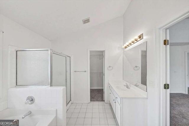 full bathroom with lofted ceiling, a shower stall, visible vents, a garden tub, and a walk in closet