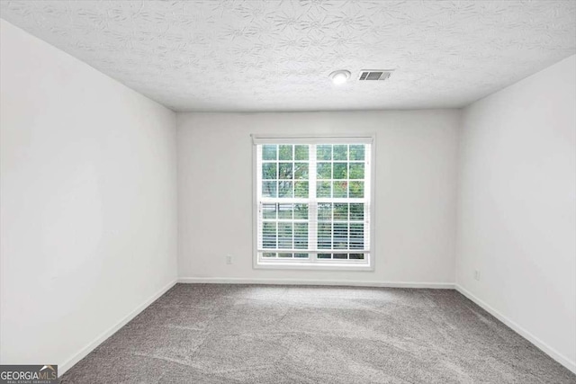 carpeted spare room with a textured ceiling, visible vents, and baseboards