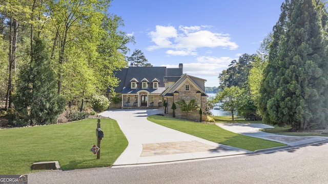 view of front of home with a chimney, concrete driveway, a front lawn, and a standing seam roof