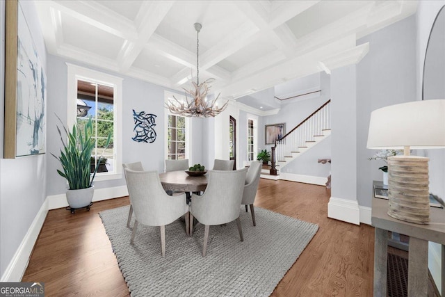 dining area with wood finished floors, stairs, coffered ceiling, a chandelier, and beamed ceiling