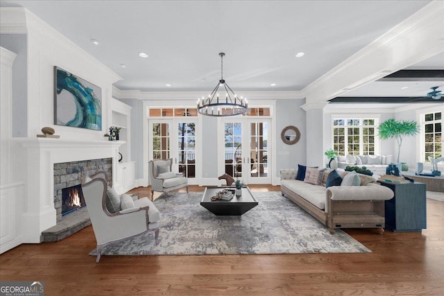 living area with crown molding, an inviting chandelier, wood finished floors, and a fireplace