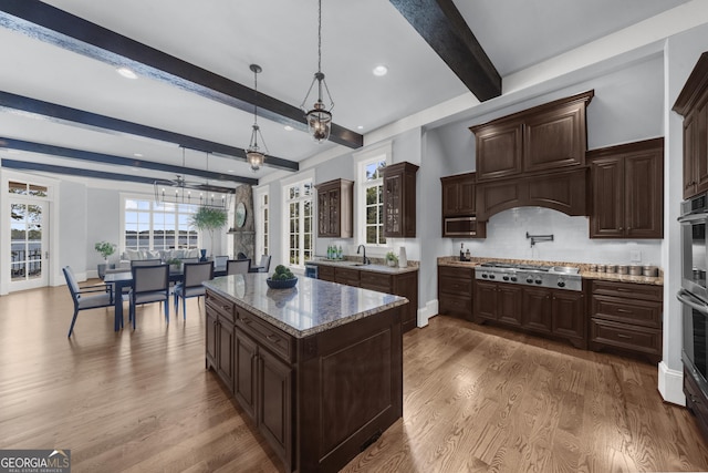 kitchen featuring beam ceiling, a chandelier, pendant lighting, appliances with stainless steel finishes, and wood finished floors