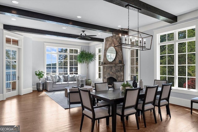 dining space with beam ceiling, wood finished floors, ceiling fan with notable chandelier, and baseboards