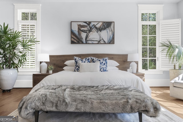 bedroom with baseboards, wood finished floors, and multiple windows