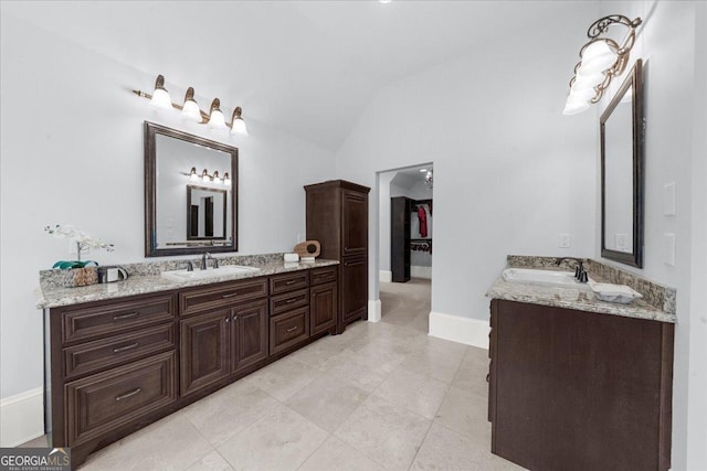 bathroom featuring two vanities, vaulted ceiling, and a sink
